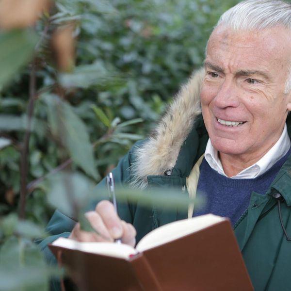 Happy senior man stretching his arms outdoors in a green park.